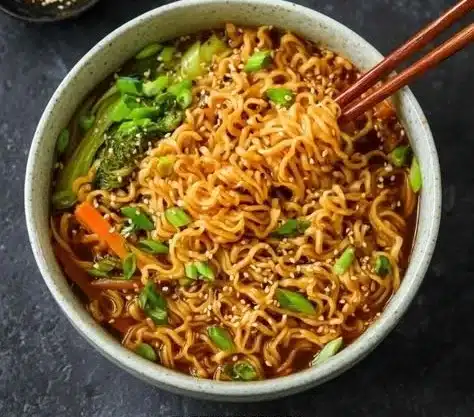 Bowl of steaming ramen noodles garnished with green onions and eggs